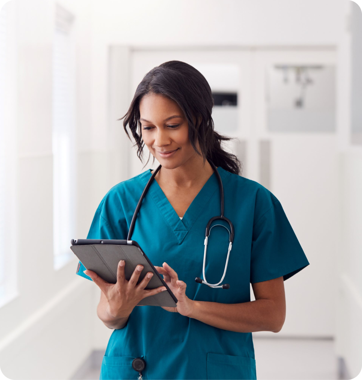 A nurse reviewing patient information on a tablet in a hospital corridor